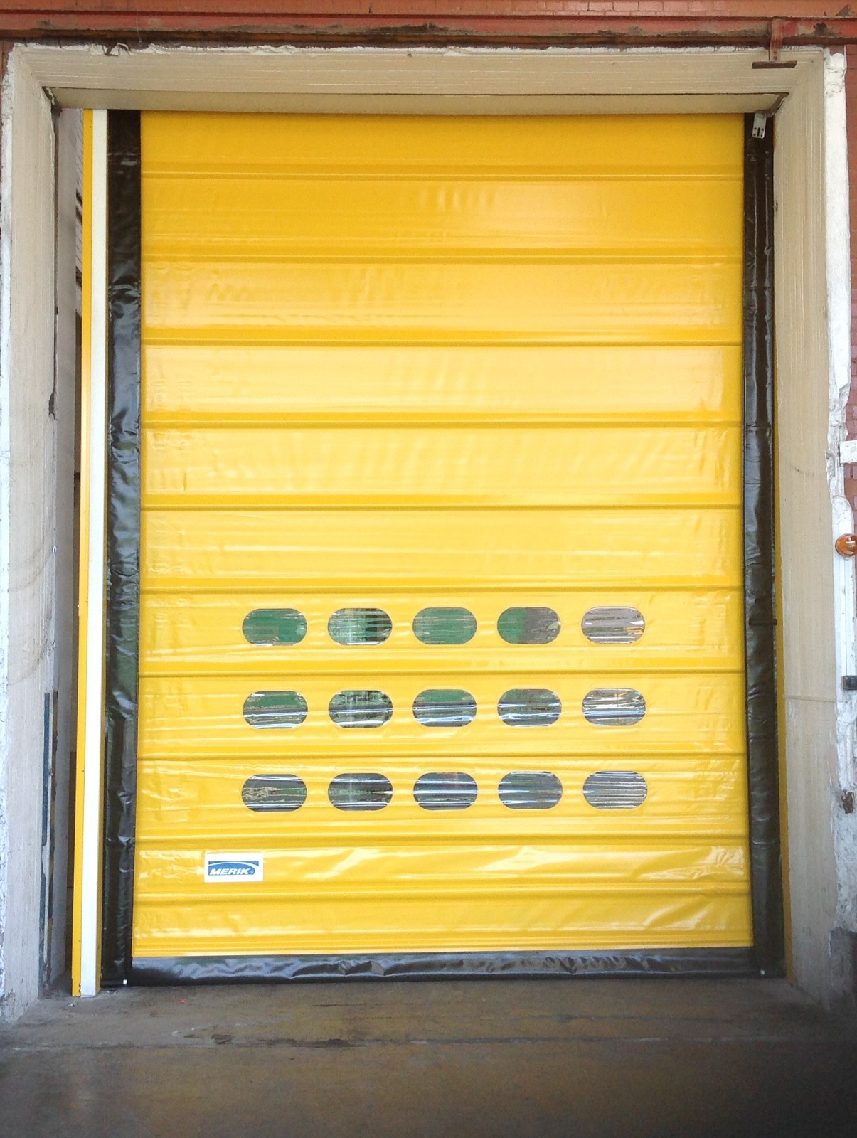 Puerta rápida industrial amarilla instalada en acceso de bodega